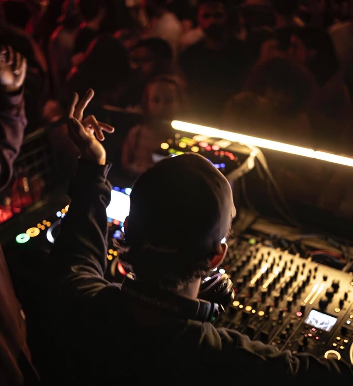 Niko Couture behind the mixer with a hand raised in the crowd